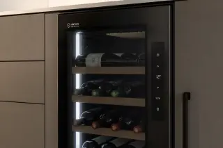 Modern wine cabinet with anti-UV glass door built under a kitchen countertop, LED lighting inside and wine bottles stored horizontally.