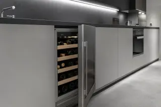 Stainless steel wine cabinet built into a modern kitchen with cold LED lighting and organized bottle storage