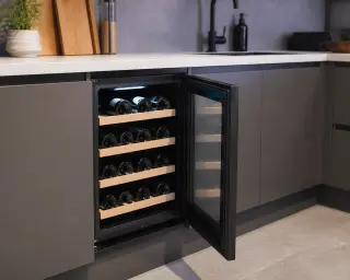 electric wine cabinet built into a modern kitchen countertop with bottles stored horizontally, under cool LED lighting
